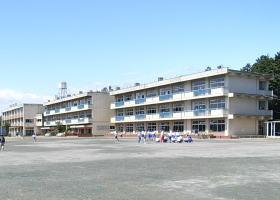 広い校庭に3階建ての小学校の校舎が3棟並んで写っている写真