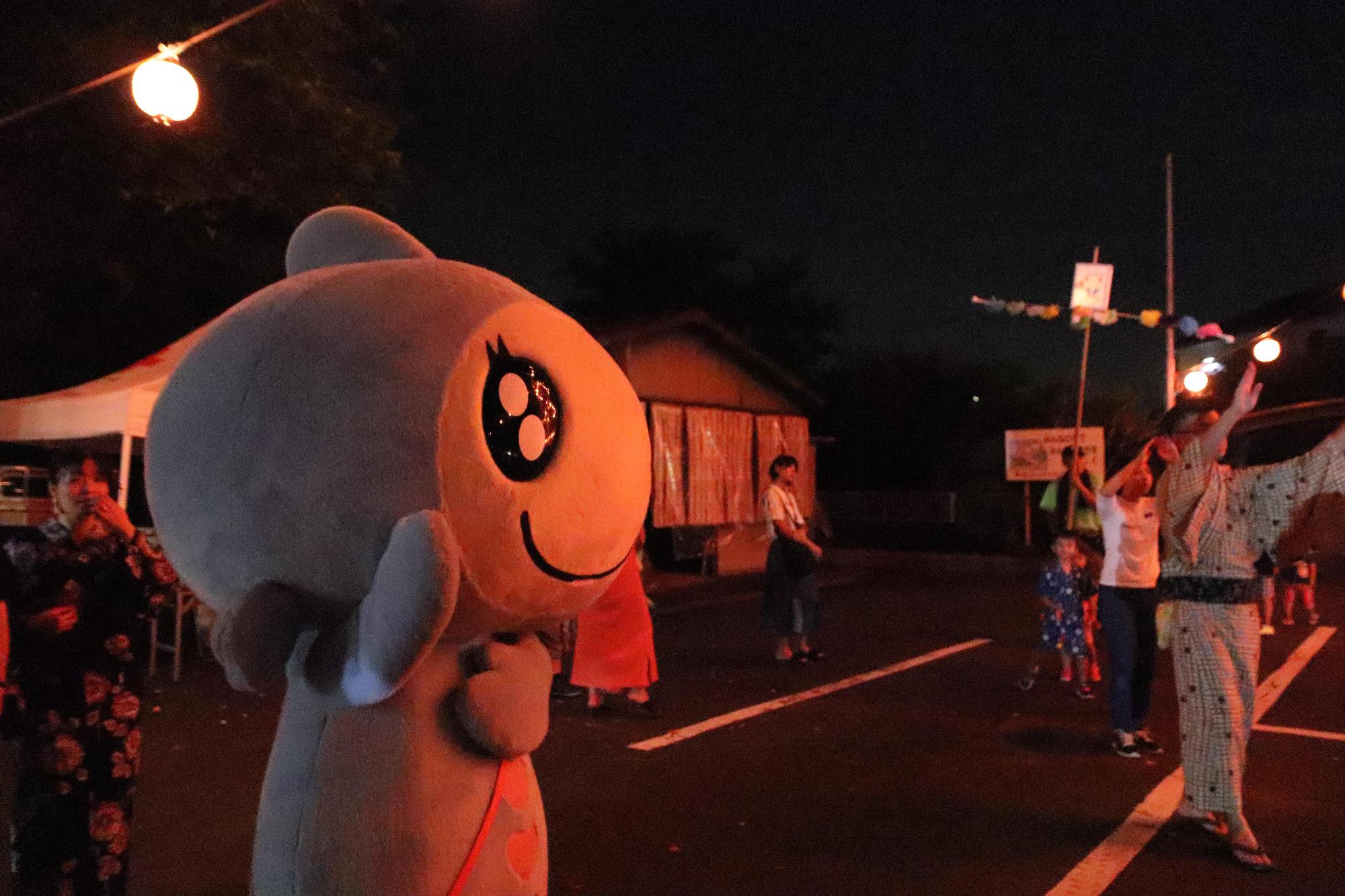 滑川町コミュニティセンター前でおこなわれた納涼盆踊り大会で地元の人々に交じって右手を掲げ左手を胸に置き踊るターナちゃんの写真