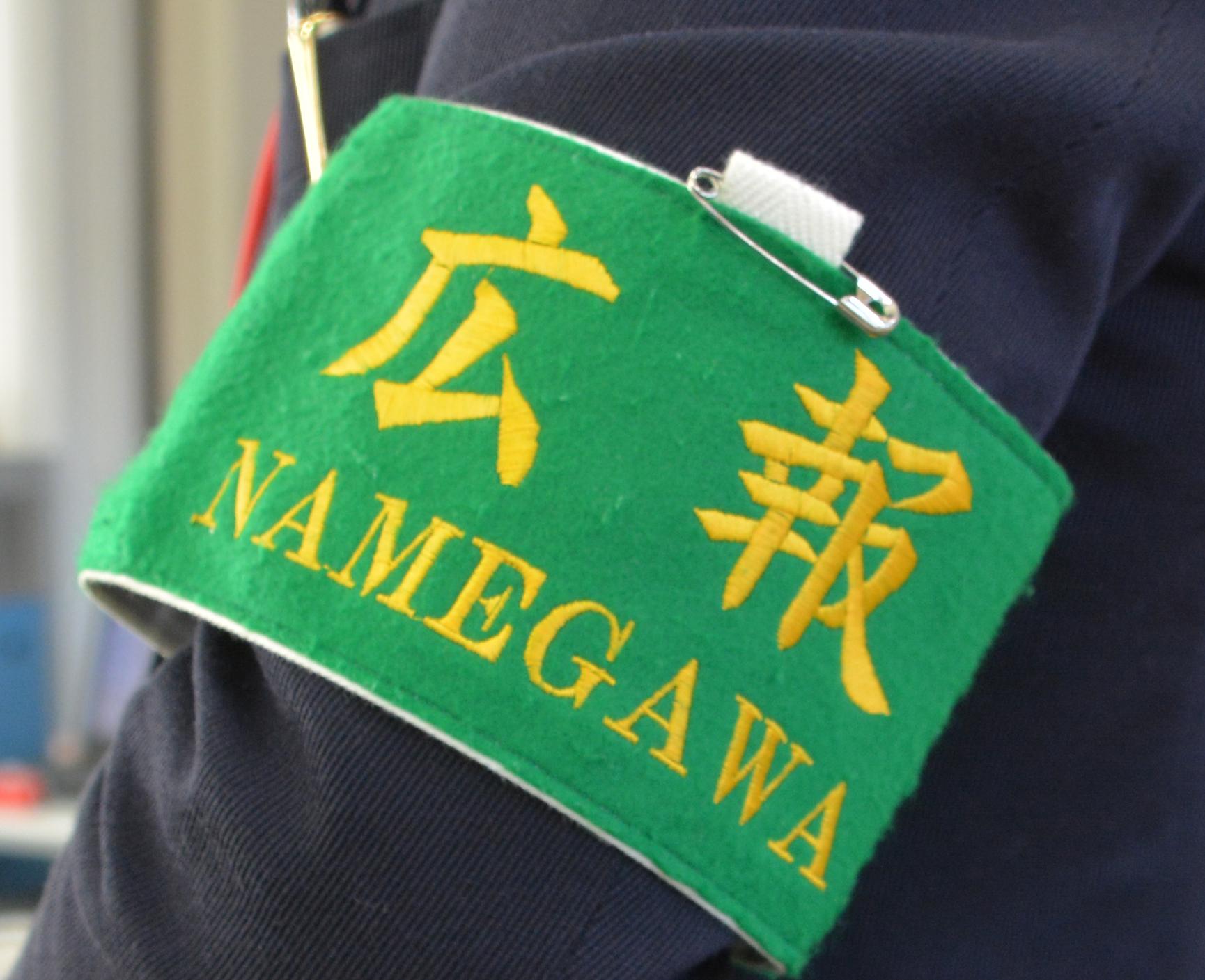 緑地に黄色で広報NAMEGAWAと書かれている腕章の写真
