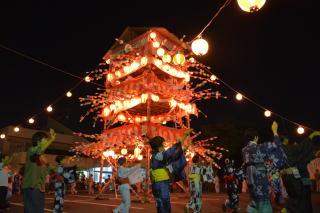 滑川町でおこなわれた盆踊り大会で丸提灯でライトアップされた三段の櫓の下で浴衣を着て踊る地元の女性たちの写真