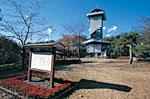 青空の下建つ二ノ宮山展望塔とその手前に立てられた案内板の写真